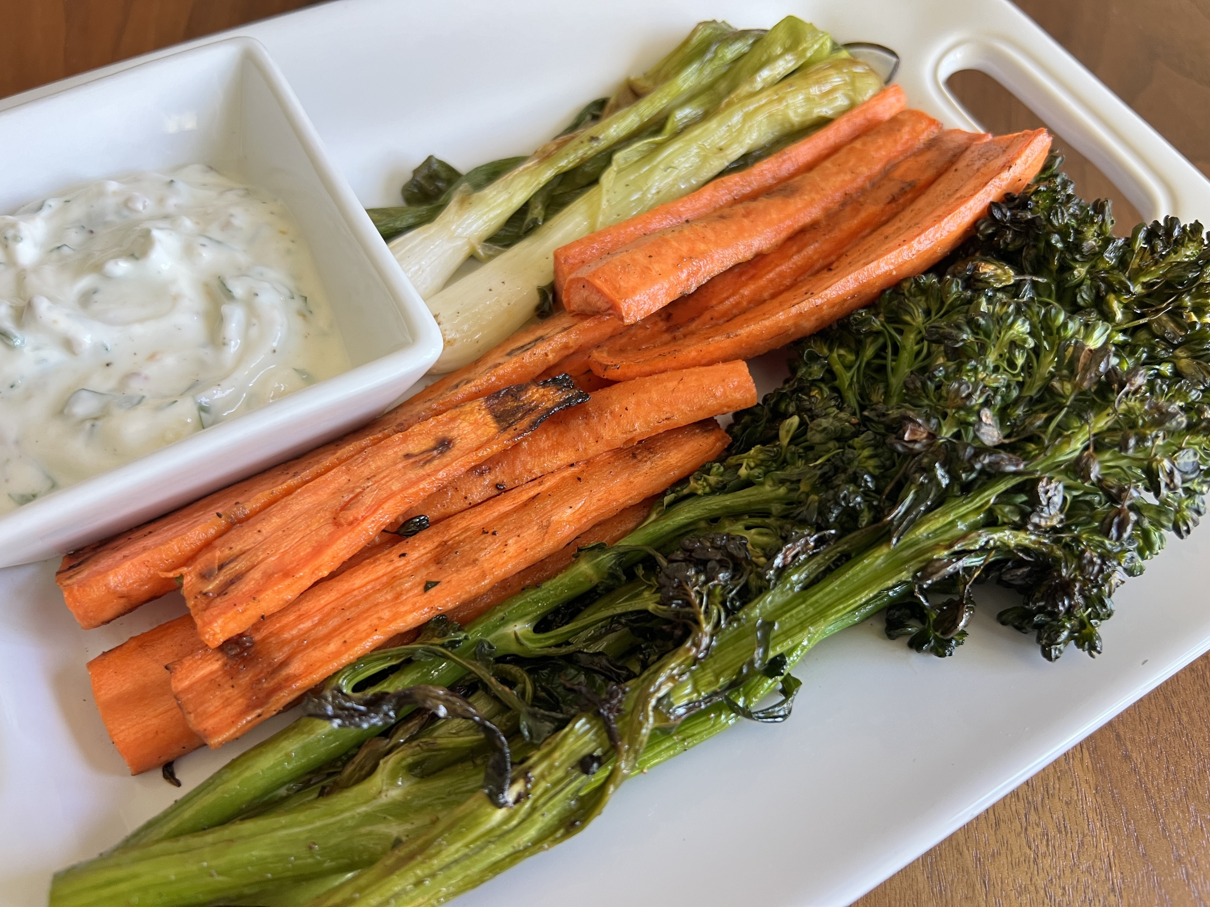 platter of grilled broccolini, carrots and green onions with a dish of mint, pistachio yogurt dressing on the side